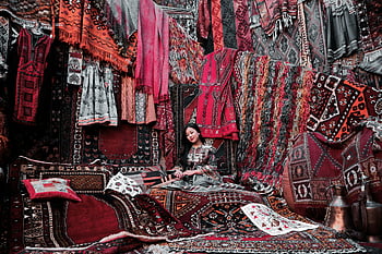 woman sitting, carpet, traditional Turkish rugs, textiles, indoor market, vibrant display, Turkish textiles, market display, woman on carpet, Turkish market, traditional rugs