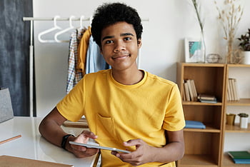 adolescent, Tricou de gât galben, Ținând tableta, învățarea online, Setare interioară, Expresie fericită, îmbrăcăminte lejeră, activitate educativă, dispozitiv digital, Mediul de origine, student zâmbind
