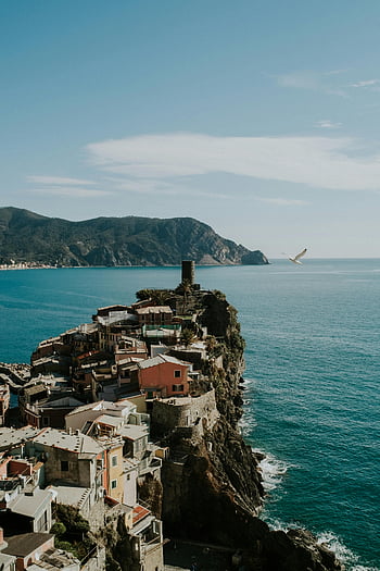 Vernazza, Cinque Terre, colorful houses, coastal view, Ligurian Sea, cliffside houses, blue sky, seaside village, Italian coastline, Mediterranean landscape, scenic coastal town