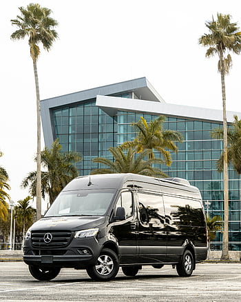 Černý Mercedes-Benz Sprinter, rok výroby 2023, městském prostředí, moderní budova, palmy, dodávka, parkoviště, venkovní, luxusní vozidlo, komerční dodávka, panoráma města, architektura