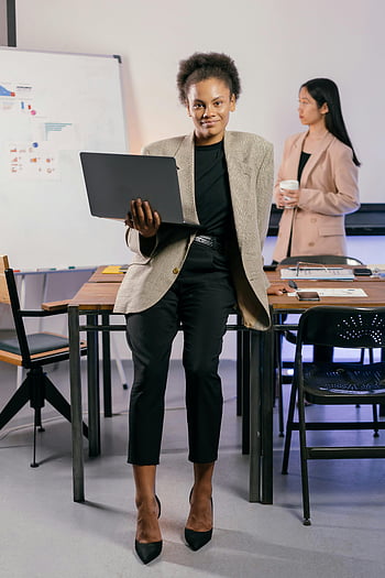 woman in black pants, holding laptop, professional woman, office attire, exuding confidence, business setting, office environment, confident pose, professional look, businesswoman, office work