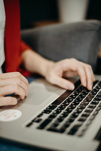 gray laptop, hands typing, office setting, close-up shot, keyboard, workspace, professional attire, red tie, computer use, focused shot, indoor environment