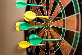 green and yellow darts, brown-black-green-and-red dartboard, bullseye, indoor sport, precision, dartboard, green darts, yellow darts, indoor scene, sport scene, darts