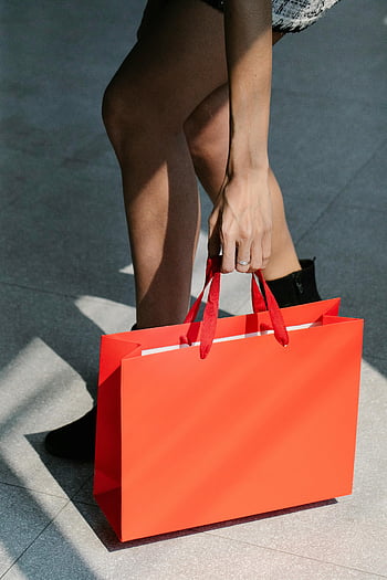 red shopping bag, stylish woman, pavement, street, vibrant red, carrying bag, walking, unrecognizable lady, ground, outdoor, fashion