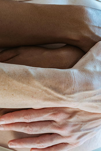 Coppia diversa, tenero abbraccio, pancia incinta, mani diverse, amore e anticipazione, pancia nuda, tonalità della pelle, momento intimo, legame familiare, maternità, gravidanza