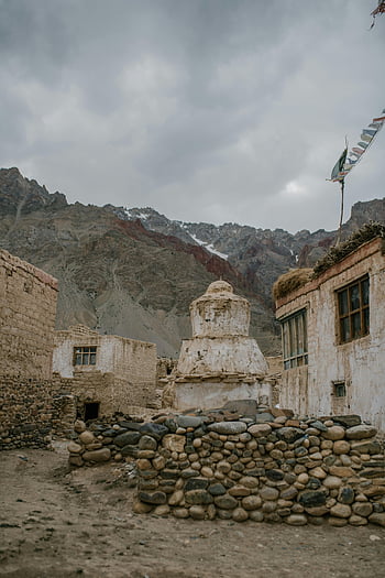 old stone pagoda, mountainous countryside, overcast sky, Tibetan village, Zanskar Valley, ancient village, serene landscape, stone houses, traditional architecture, cultural heritage, natural beauty