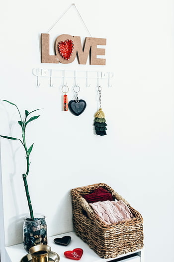 decorative trinkets, wicker basket, plant, white background, contemporary home interior, LOVE sign, cozy atmosphere, hanging hooks, keychains, bamboo plant, heart-shaped decor