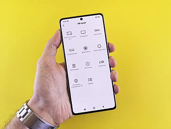 hand holding smartphone, tech interface, vibrant yellow background, close-up hand, smartphone display, tech icons, smart device, modern technology, user interface, smart phone, yellow backdrop