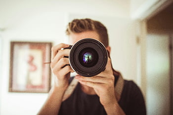 person holding DSLR camera, photographer, camera lens, indoor photography, man taking photo, close-up shot, photography hobby, camera equipment, photo shoot, indoor setting, portrait photography