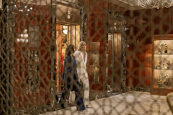 luxurious hotel interior, elegantly dressed women, elevator exit, stylish hall, woman in blue suit, woman in white coat, hotel lobby, elegant attire, modern interior design, chandelier lighting, marble walls