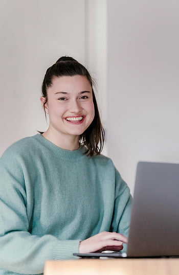 lächelnde Frau, Arbeiten am Laptop, gemütlicher Pullover, Heimarbeit, moderner Lebensstil, fröhliche junge Frau, Innenministerium, Laptop-Arbeit, Von zuhause aus arbeiten, Freizeitbekleidung, Heimarbeitsplatz