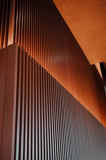 modern building facade, geometric patterns, warm lighting, vertical facade, close-up view, architectural design, contemporary architecture, modern architecture, building exterior, architectural details, warm tones