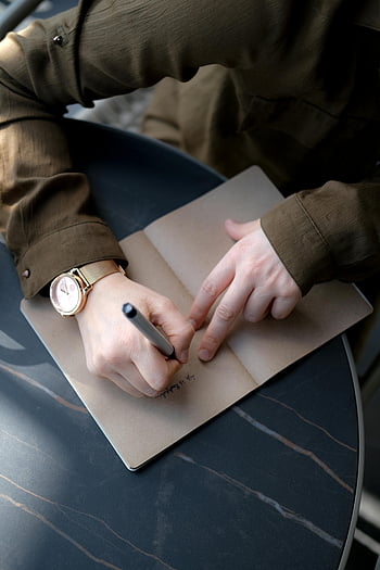 writing on notebook, close-up shot of hands, detailed shot of hands writing, stylish table setting, note-taking with pen, person writing notes, pen and paper, closeup of writing, hands taking notes.