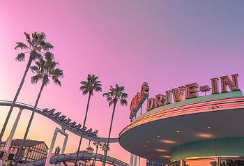 theme park, roller coaster, palm trees, low angle shot, pink twilight skies, vibrant scene, drive-in, amusement park, sunset, evening, entertainment