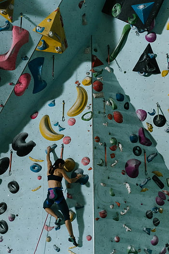woman rock climbing, indoor rock wall, gym setting, colorful holds, skillful climber, focused climber, indoor climbing gym, rock climbing gym, climbing holds, indoor bouldering, female climber