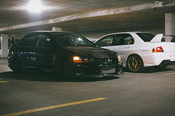 Evoluce Mitsubishi Lancer, podzemní garáže, zaparkovaná auta, osvětlené parkoviště, dvě auta, Vozidla Mitsubishi, Performance Cars, Automobiloví nadšenci, automobilové fotografie, Osvětlení garáže, bílá a černá auta