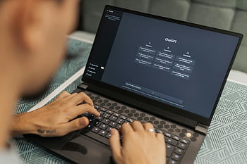 man using laptop, ChatGPT interface, modern technology use, close-up typing, laptop display, person typing, ChatGPT, technology use, modern technology, laptop screen, hands typing