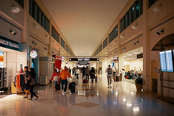 airport terminal, people at airport, busy airport, indoor travel, airport hallway, crowds navigating, bright airport, travel dynamics, airport shops, flight information, airport passengers