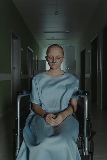 kvinde i kørestol, hospital kjole, dunkel hospitalskorridor, patient siddende, følelsesmæssige udtryk, iltmaske, Medicinsk ramme, sundhedsmiljø, kørestolsbundet patient, hospital korridor, lægebehandling