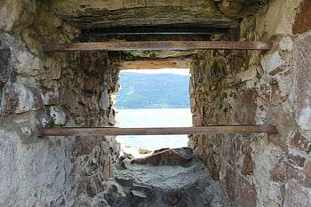 barred window, castle window, window with bars, stone wall, medieval architecture, ocean view, historic structure, ancient building, stone castle, barred opening, scenic landscape