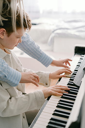 leçon de piano, professeur de musique, adolescent pratiquant, touches de piano, cadre intérieur, orientation du mentor, environnement chaleureux, éducation musicale, pratique du piano, garçon apprenant, enseignement de la musique