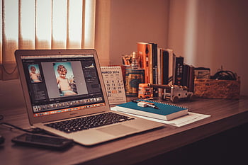 Macbook Air, wooden desk, home office, freelancer workspace, laptop setup, warm-toned desk, notebook, books, desk organization, photo editing, workspace inspiration