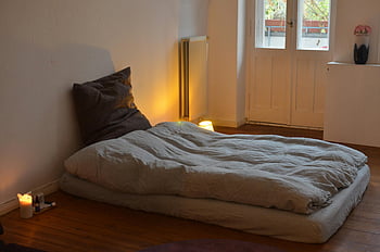 minimalist bedroom, cozy bedding, warm lighting, subtle decor, inviting bedroom, floor mattress, wooden floor, soft lighting, modern bedroom, simple decor, home interior