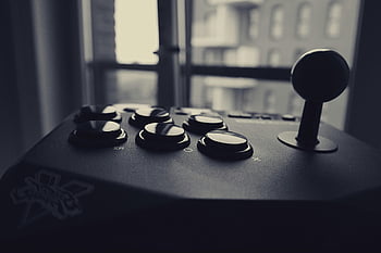 gray scale arcade controller, black and white, retro gaming joystick, cityscape background, close-up, arcade buttons, gaming controller, vintage gaming, joystick, arcade machine, black and white photography