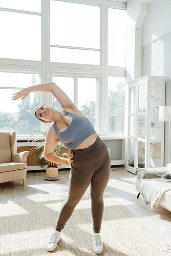 Kvinne som trener hjemme, pluss størrelse kvinne, stretching, lys stue, Kroppspositivitet, sunn livsstil, hjemme trening, Fitness, yoga, innendørs trening, aktiv livsstil