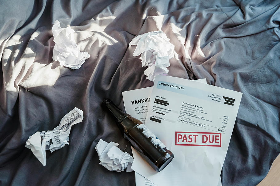 distress, bankruptcy notice, past due bills, crumpled papers, beer bottle, bed scene, statement bills, financial trouble, overdue payments, financial crisis, debt problems